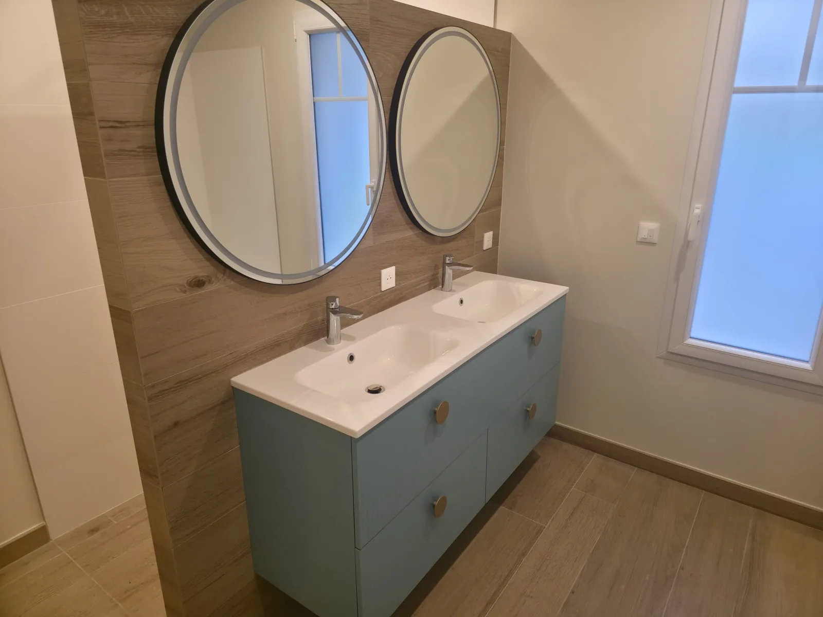 Salle de bain avec double vasque, miroirs ronds et mur en bois