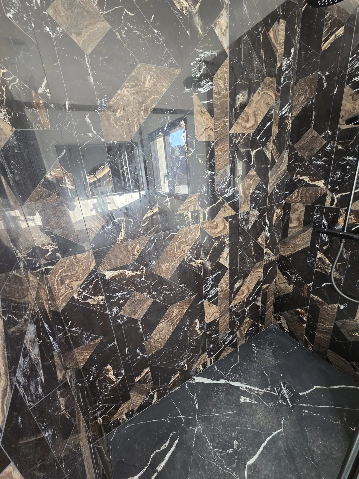 Salle de bain en marbre noir et or posée par AS de Bâtiment